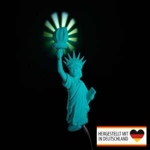 Leuchtende Wandlampe „Freiheitsstatur“ mit strahlender Fackel vor dunkler Wand